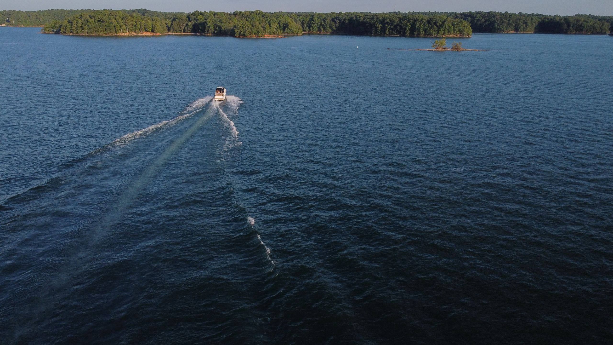 Captivating aerial view of a boat cruising on Lake Lanier surrounded by lush greenery in Georgia.